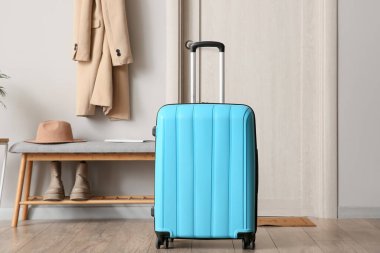 Koridorun iç tarafındaki kapının yanına mavi bavul yerleştirilmiş.