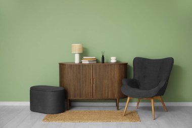 İçinde puf, çekmece sandığı ve yeşil duvarın yanında siyah koltuk olan oturma odası.