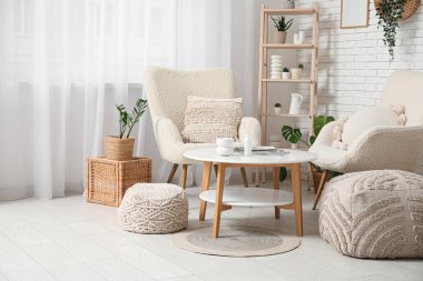 Oturma odasının iç tarafında masa ve beyaz koltuklar.