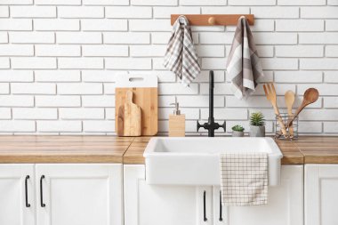 Mutfaktaki beyaz tuğla duvarın yanında lavabo ve temiz peçetelerle tezgahlar.