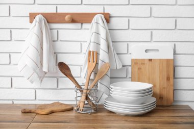 Kaseler ve ahşap çatal bıçaklar tezgahlarda ve temiz peçeteler mutfakta beyaz tuğla duvarda asılı.