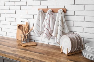 Tabaklar, tezgahlardaki çatal bıçak ve mutfaktaki beyaz tuğla duvara asılı temiz peçeteler.