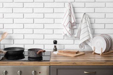 Tezgahlardaki aletler ve elektrikli soba ve mutfaktaki beyaz tuğladan duvara asılı temiz peçeteler.