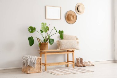 Koridorun iç tarafındaki beyaz duvarın yanında minderleri ve bitkileri olan bir bank.