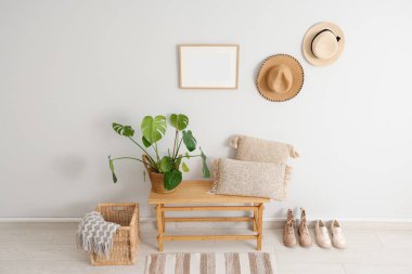 Koridorun iç tarafındaki beyaz duvarın yanında minderleri ve bitkileri olan bir bank.