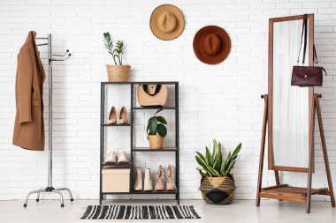 Koridorun iç tarafındaki beyaz tuğla duvarın yanındaki raf ve zemin aynası.