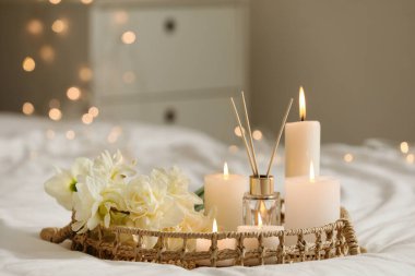 Sazlık ayırıcılı tepsi, yatak odasında yanan mumlar ve çiçekler, yakın plan.