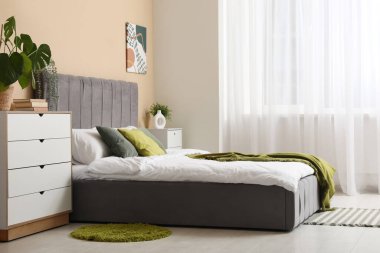 Pencerenin yanında rahat yatak odası ve çekmeceleri olan modern yatak odası.