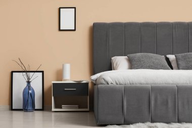 Yatak odasının içindeki bej duvarın yanında rahat bir yatak, yakın plan.