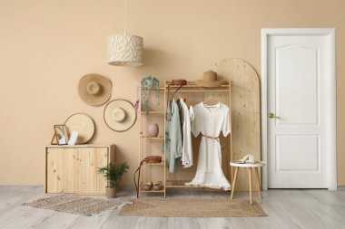 Koridorun iç tarafındaki bej duvarın yanında giysi ve aksesuarlarla dizilin.