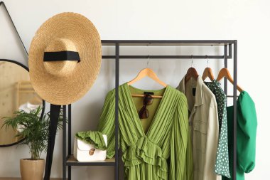 Koridordaki beyaz duvarın yanında giysi ve aksesuarlarla dizilin.