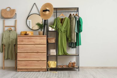 Koridorun iç tarafındaki beyaz duvarın yanında giysi ve aksesuarlarla dizilin.