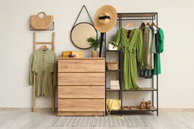 Koridorun iç tarafındaki beyaz duvarın yanında giysi ve aksesuarlarla dizilin.