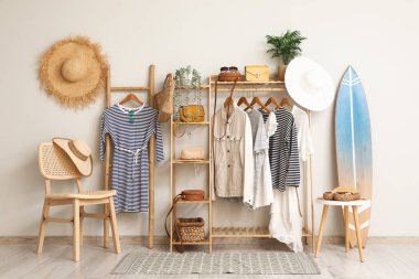 Sörf tahtası ve askılık. Koridorun iç tarafındaki beyaz duvarın yanındaki kıyafetler.