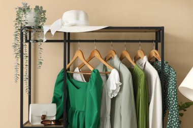 Koridordaki bej duvarın yanında giysi ve aksesuarlarla dizilin.