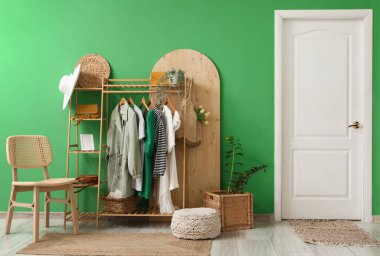 Koridorun iç tarafındaki yeşil duvarın yanında giysi ve aksesuarlarla dizilin.