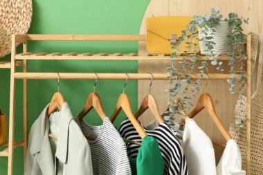 Koridordaki yeşil duvarın yanında giysi ve aksesuarlarla dizilin.