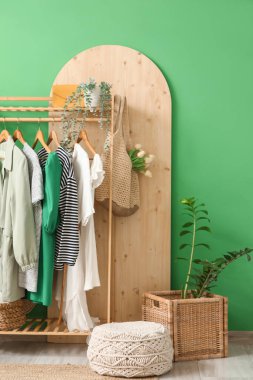 Koridorun iç tarafındaki yeşil duvarın yanında giysi ve aksesuarlarla dizilin.