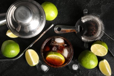 Bir bardak soğuk Küba Libre kokteyli ve siyah arka planda limon.