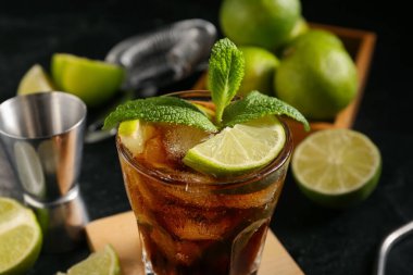 Siyah arka planda naneli ve limonlu soğuk Küba Libre kokteyli.