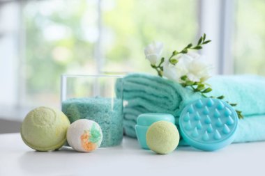 Deniz tuzu, banyo bombaları, havlular, çiçekler ve masajlı vücut fırçası banyoda, yakın plan.