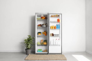 Mutfağın içinde beyaz duvarın yanında ürünleri olan büyük bir buzdolabı aç.