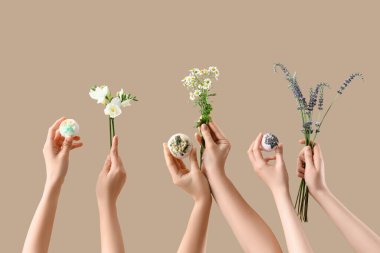 Banyo bombalı kadın elleri ve bej arka planda farklı çiçekler.