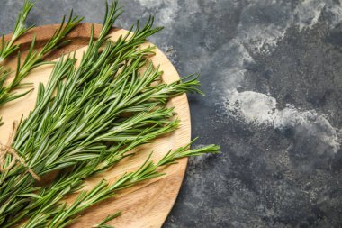 Gri grunge arka planında bir demet taze biberiye olan ahşap tahta.