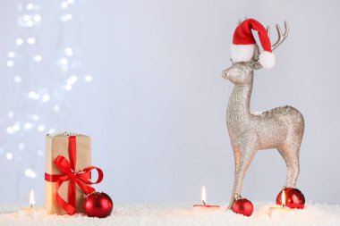 Hediye kutulu kompozisyon, dekoratif geyik, parlayan mumlar ve beyaz duvarlı Noel topları, yakın plan.