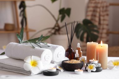 Tesisat çiçekleri, temiz havlular ve banyodaki kanepede yanan mumlar, yakın çekim.