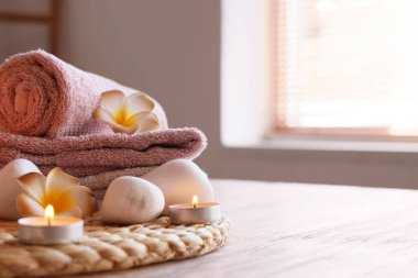 Hasır hasırlar, tesisat çiçekleri, spa taşları, yanan mumlar ve kaplıca salonundaki ahşap masa üzerindeki temiz havlular.