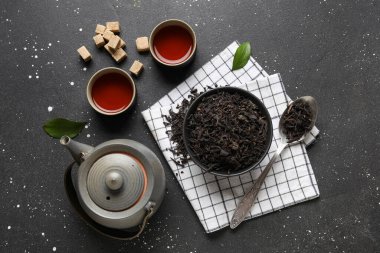 Siyah çay fincanları ve koyu yapraklı kase.