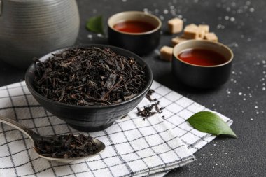 Siyah çay fincanları ve koyu arka planda kuru yapraklar, yakın plan.