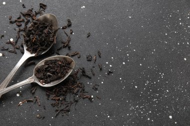 Siyah çay yapraklı kaşıklar koyu arkaplanda