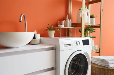 Modern çamaşır makinesi, çekmece sandığı ve banyonun içindeki raf ünitesi, yakın çekim.