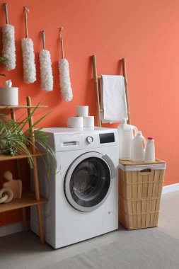 Modern çamaşır makinesi, çamaşır sepeti ve banyoda bir şişe deterjan, yakın çekim.