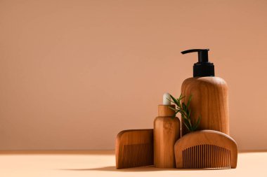 Ahşap saç tarakları, biberiye dalı ve bej arka planda kozmetik ürünler içeren kompozisyon, yakın plan