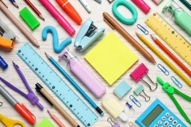 Beyaz ahşap arka planda boş notlar ve okul malzemeleri, yakın plan.