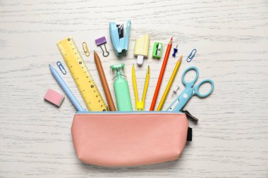 Beyaz ahşap arka planda okul kırtasiyesi olan kalem kutusu, yakın plan.