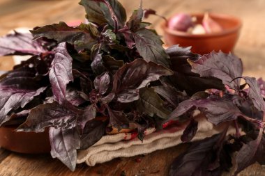 Ahşap arka planda taze mor fesleğen yapraklı tabaklar, yakın plan.