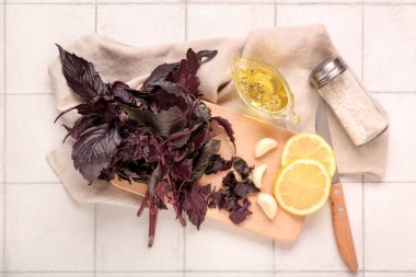 Taze mor fesleğen yapraklı ahşap tahta, sarımsak ve beyaz fayanslı limon dilimleri.