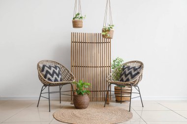 Katlanan ekran, hasır koltuklar ve oturma odasının içinde saksılar.