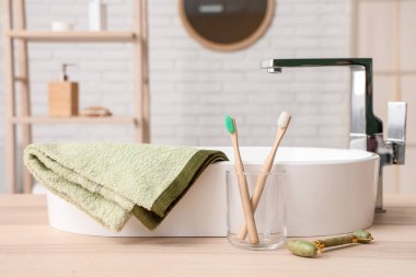 Diş fırçalı cam bardak, yeşim taşlı rulo ve banyodaki lavabo, yakın plan.