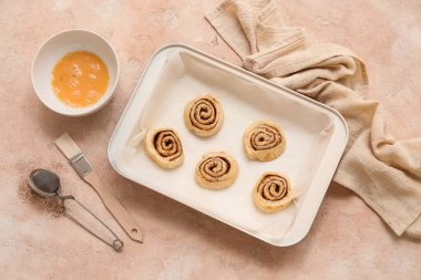 Pembe arkaplanda çiğ tarçınlı çörekler pişirme tepsisi