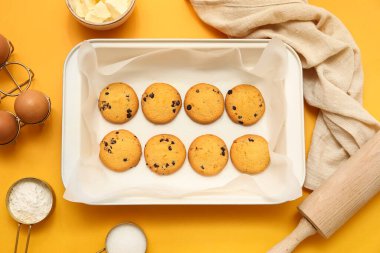 Yemek tepsisi, lezzetli kurabiyeler ve sarı arka planda malzemeler.