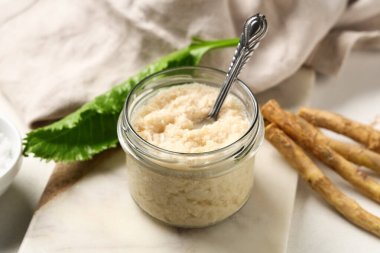 Beyaz grunge arka planda yabanturpu soslu mermer tepsi ve kase, yakın plan.