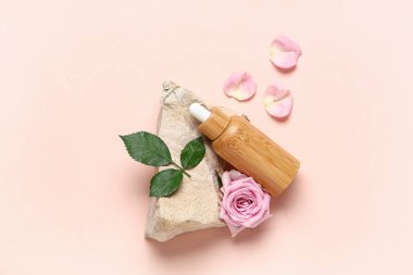 Dekoratif taşlı kompozisyon ve pembe arka planda gerekli gül yağı.