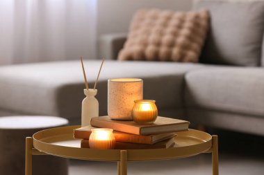 Kitaplar, kamış ayırıcı ve mumlar oturma odasının iç tarafında, yakın plan.