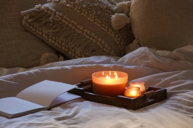 Kitap ve tepside yanan mumlar karanlık yatak odasında, yakın çekim.