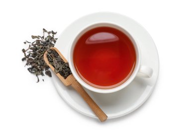 Siyah çay ve kepçeyle beyaz arka planda kuru yapraklar, yakın plan.